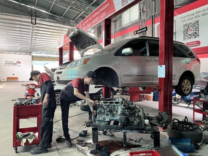 Hai người thợ sửa chữa ô tô tại gara đang kiểm tra kỹ thuật chờ linh kiện phụ tùng về để thay thế